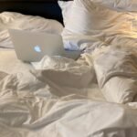 an apple laptop sitting on top of a bed