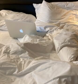 an apple laptop sitting on top of a bed