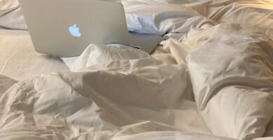 an apple laptop sitting on top of a bed