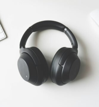 black wireless headphones between Apple Keyboard and Apple Magic Mouse on white surface