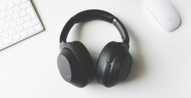 black wireless headphones between Apple Keyboard and Apple Magic Mouse on white surface